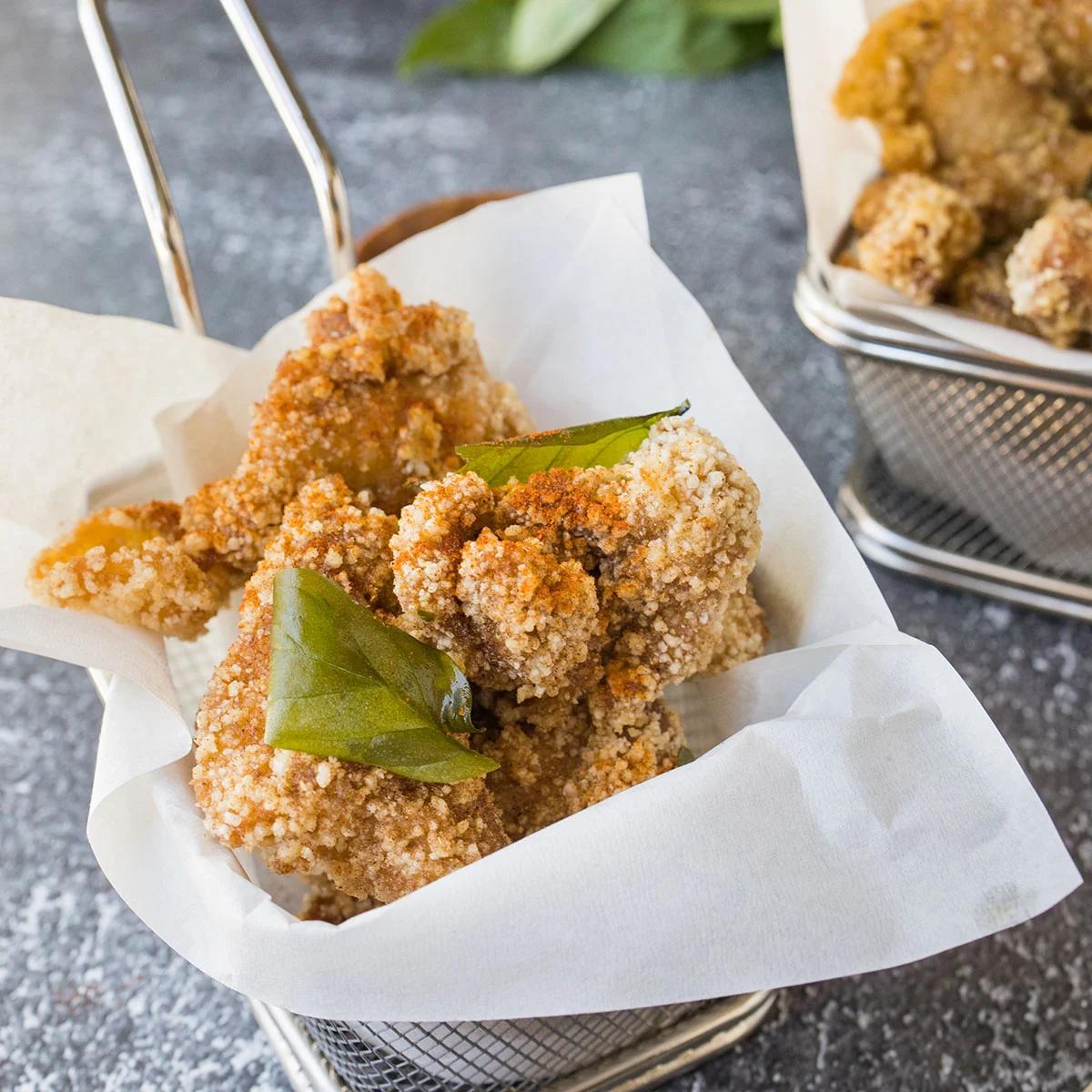 Crispy Taiwanese popcorn chicken with basil leaves in a paper-lined basket