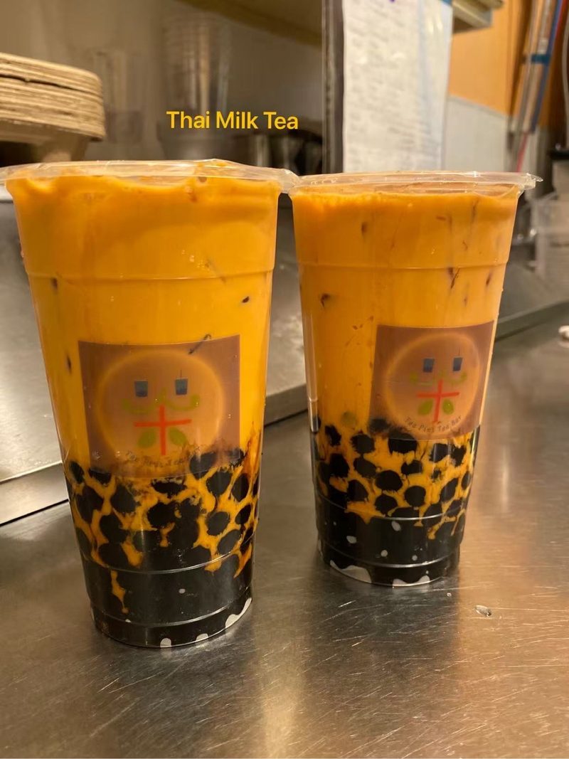 Two cups of Thai milk tea with boba, fresh off the counter